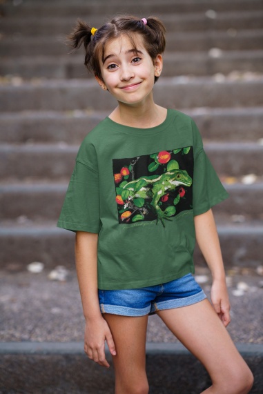 A young girl in a forest green jewelled gecko teeshirt posing in front of concrete stairs.