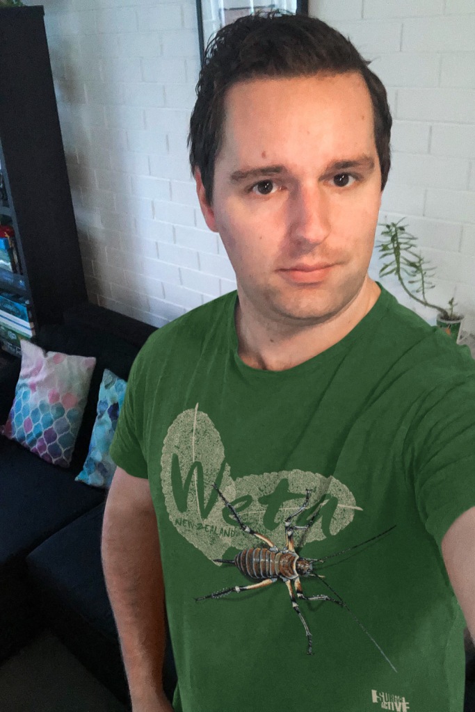 Selfie of a man wearing a forest green weta, New Zealand t-shirt.
