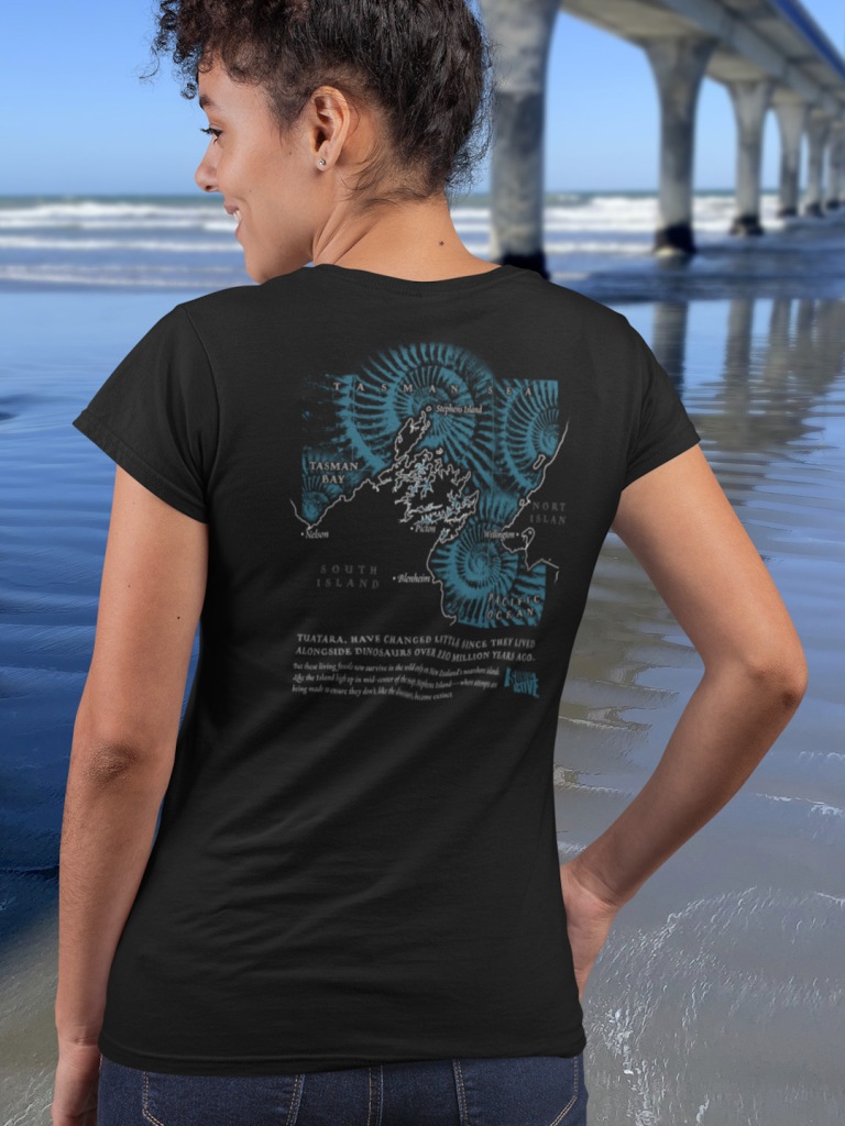 Back view of a curly haired young woman wearing her Surface Active Tuatara t-shirt beside the New Brighton pier.